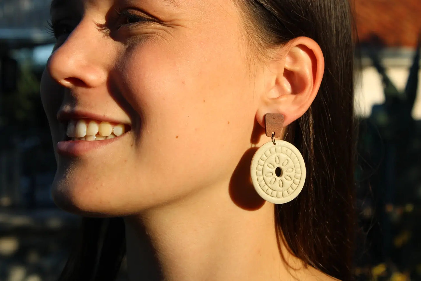 Close-up of a woman wearing a gold earring with a circular design.