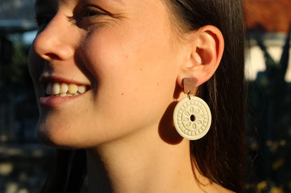 Close-up of a woman wearing a gold earring with a circular design.